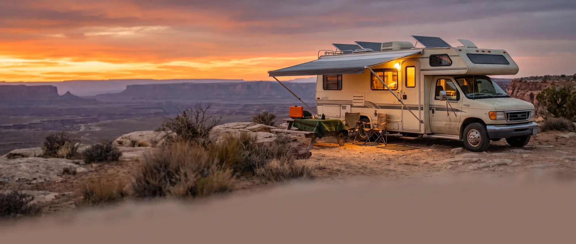 Camper RV boondocking at a scenic desert overlook at sunset with rooftop solar